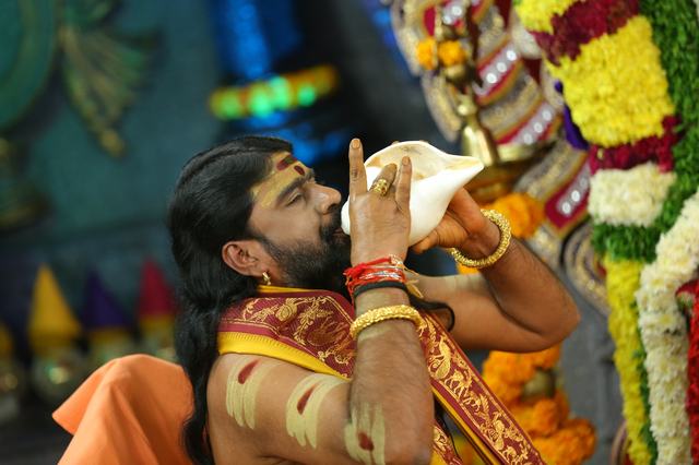 Guruji blowing the sacred conch during a celebration